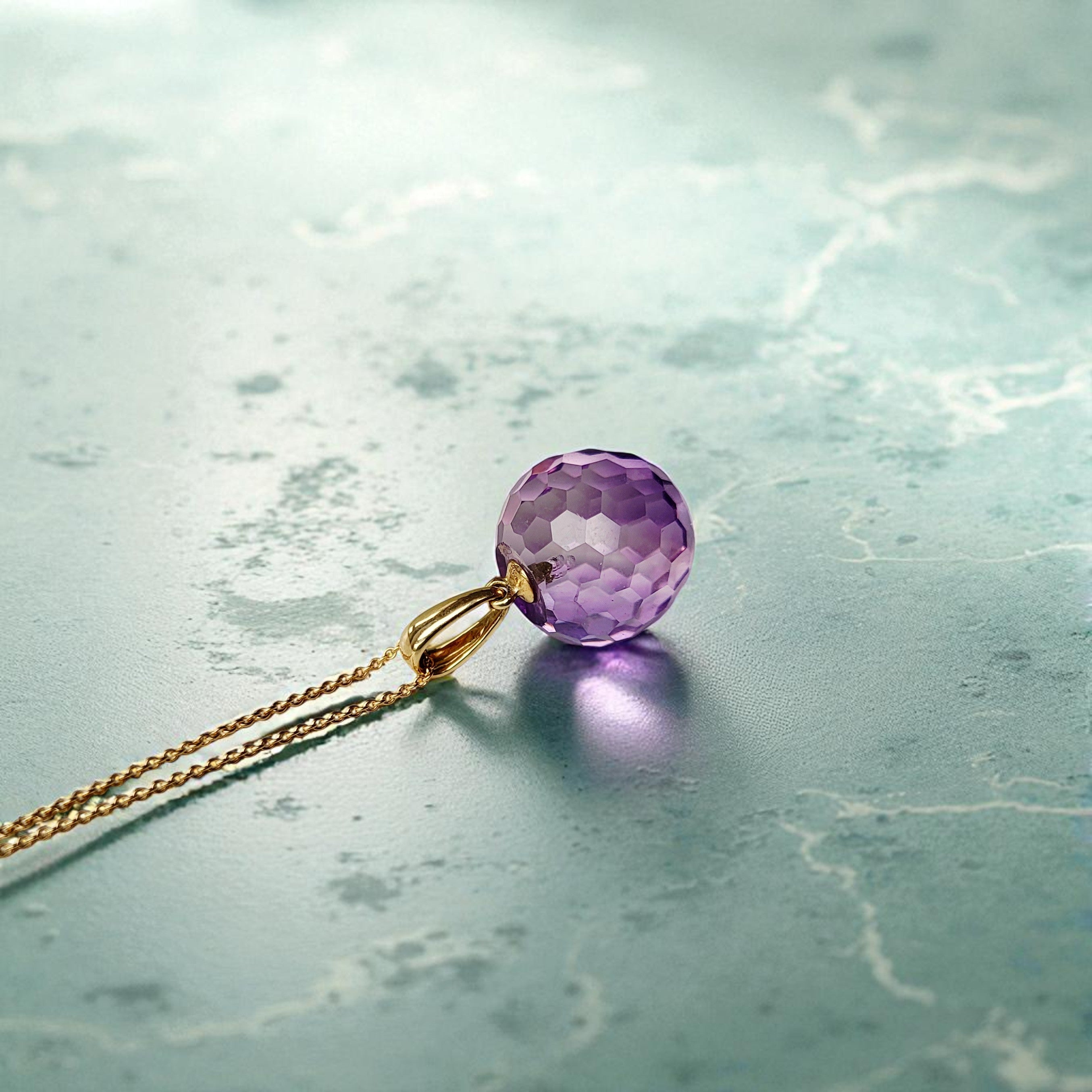 Edelsteinanhänger Amethyst Kugel 21mm mit Halskette in 585 Gold auf grünem Marmor