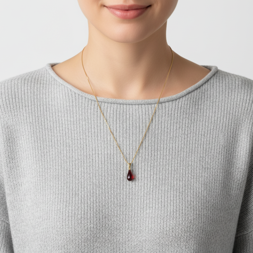 Frau mit grauem Pullover trägt eine Halskette aus 585 Gold mit einem Edelsteinanhänger Granat Tropfen 21 mm
