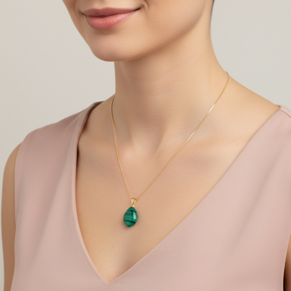 Eine Frau mit rosa Top trägt eine Halskette aus 585 Gold und einen Edelsteinanhänger aus Malachit als glatte Briolette